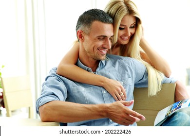 Young Couple Reading Magazine At Home