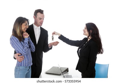 Young Couple Receives Keys From Female Real Estate Agent In Studio With White Background