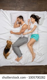 Young Couple Relaxation On The Bed Top View With A Dog Sleeping