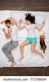 Young Couple Relaxation On The Bed Top View With A Dog Sleeping