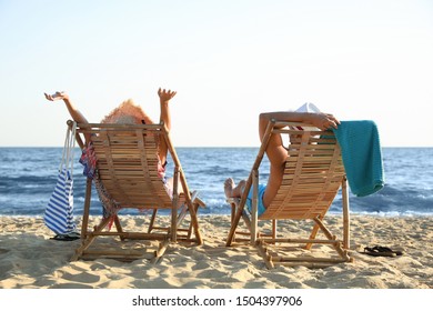 Young couple relaxing in deck chairs on beach near sea - Shutterstock ID 1504397906