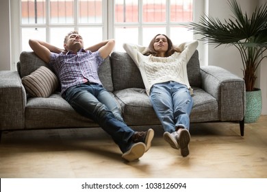Young couple relaxing having nap or breathing fresh air, relaxed man and woman enjoying rest on comfortable sofa in living room, happy family leaning on soft couch taking break for dozing together
