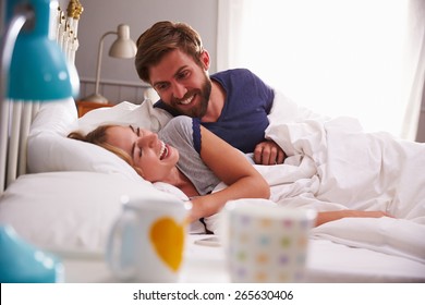 Young Couple Relaxing And Laughing In Bed Together