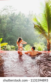 Young Couple Relaxing In Luxury Private Infinity Pool With Amazing Jungle View From Above In Bali