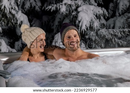 young couple relaxing in spa outdoor hot tub in winter
