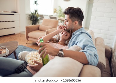 Young Couple Relaxing In Their Apartment,lying On The Couch,watching A Movie And Eating Popcorn.