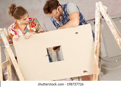 Young Couple Renovating Home, DIY, Rasping Wooden Panel.