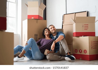 Young couple resting after moving into a new home and daydreaming. Multiethnic contemplative couple sitting on floor and thinking  while looking up. Happy couple buy new apartment and plan a family. - Powered by Shutterstock