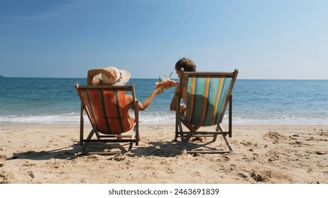 Young couple resting in a beach chairs and drinking refreshing fruit cocktails - Powered by Shutterstock