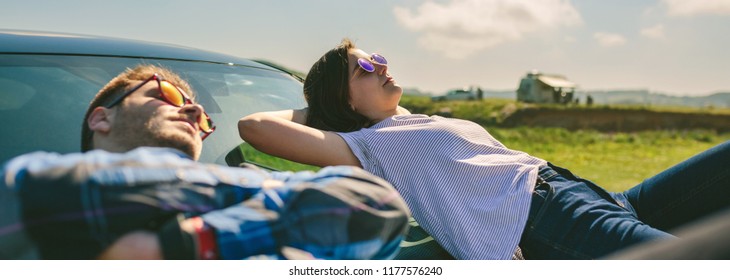 Young couple resting lying on the windshield and the hood of the car - Powered by Shutterstock