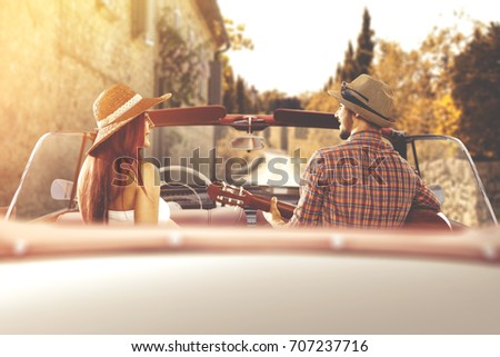 Young couple in retro cabrio car in autumn sunset