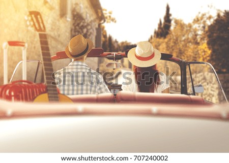 Young couple in retro cabrio car in autumn sunset
