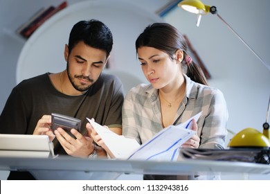 Young couple reviewing invoices and doing family business plan. Concept of money and economic problem for man and woman living together - Powered by Shutterstock