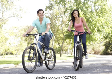 Young Couple Riding Bike In Park