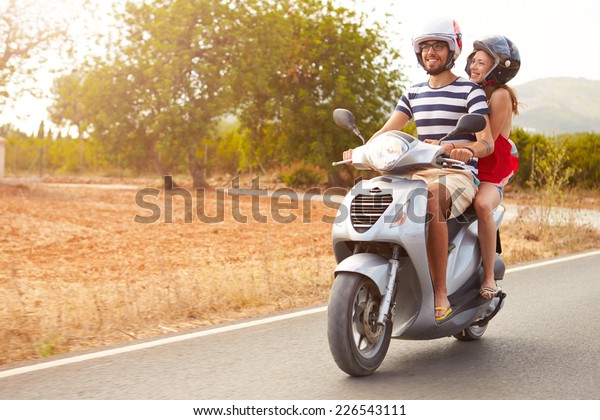 Young\
Couple Riding Motor Scooter Along Country\
Road