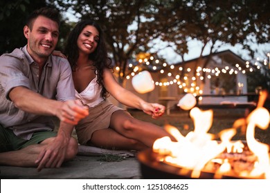 Young Couple Roasting Marshmallows Over A Fire