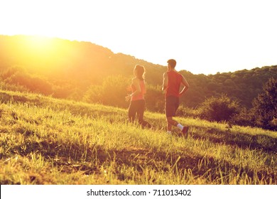 Young Couple Running In Nature On Sunset And Having Fun.