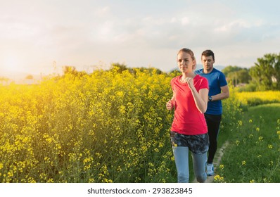 Young Couple Running Outside In Spring Canola Field