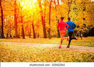 Young Couple Running Together In Park - Fall Nature