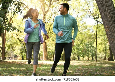 Young couple running together in park. Young people exercising.