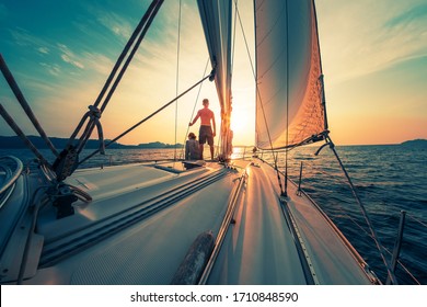 Young couple sailing on the boat at sunset
