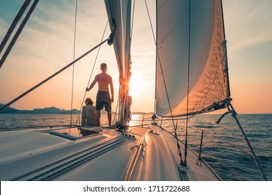 Young Couple Sailing On The Boat At Sunset