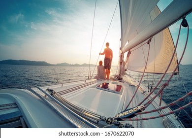 Young Couple Sailing In The Tropical Sea At Sunset On Their Yacht