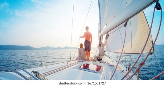 Young Couple Sailing In The Tropical Sea At Sunset On Their Yacht