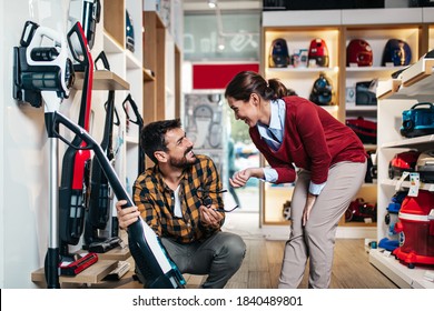 Young Couple, Satisfied Customers Buying Robotic Vacuum Cleaner In Appliances Store.