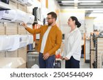 Young couple, satisfied customers choosing air conditioner in appliances store.