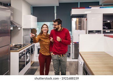 Junge Ehepaare, zufriedene Kunden, die Kühlschränke in Haushaltsgeräten auswählen.
