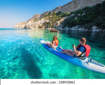 Young couple sea kayaking near the mountain coast. - Powered by Shutterstock