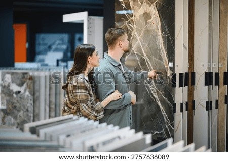 Young couple selecting marble pattern ceramic tiles in a showroom, planning new interior design for their home