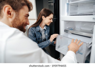 Young Couple Selecting New Refrigerator In Household Appliance Store