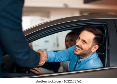 Young couple shaking hands after a successful car buying