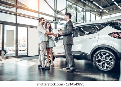 Young couple shaking hands with sales agent after a successful car buying. - Shutterstock ID 1214543995