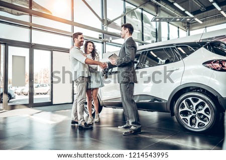Young couple shaking hands with sales agent after a successful car buying.