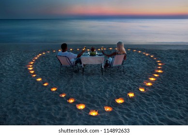 A Young Couple Share A Romantic Dinner With Candles Heart On The Sea Sand Beach