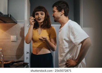 A young couple shares a joyful cooking experience in a modern kitchen, savoring the taste of their meal. The scene captures togetherness, culinary skills, and a love for homemade food. - Powered by Shutterstock