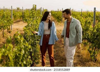 Young couple shares a joyful moment among verdant vines, laughing and embracing under the warm sun, celebrating love and the serenity of a picturesque vineyard - Powered by Shutterstock