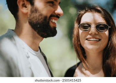 A young couple shares a light-hearted moment in the park, radiating joy and positivity under the sun, dressed in casual clothing. - Powered by Shutterstock