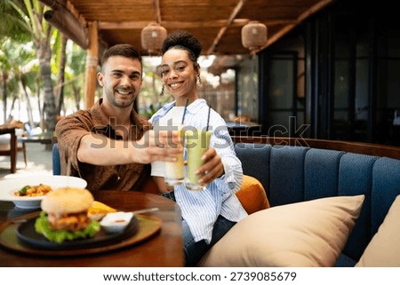 Young couple sharing dining experience at tropical restaurant, engaging with their online followers