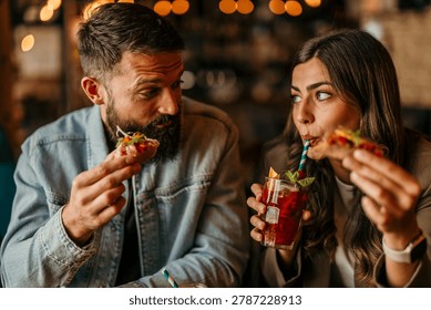 Young couple sharing tapas and drinks, enjoying a date night out
