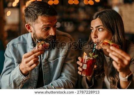 Young couple sharing tapas and drinks, enjoying a date night out