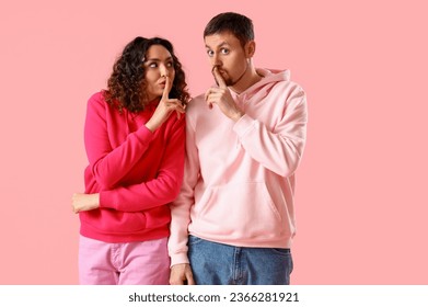 Young couple showing silence gesture on pink background - Shutterstock ID 2366281921