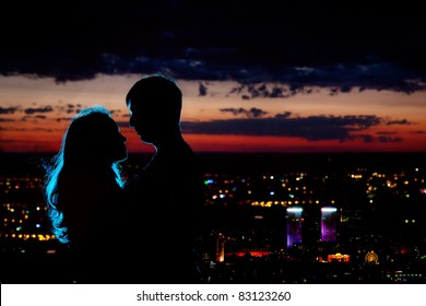 Young Couple Silhouette Hugging And Looking At Each Other Outdoors At Night Neon City Background