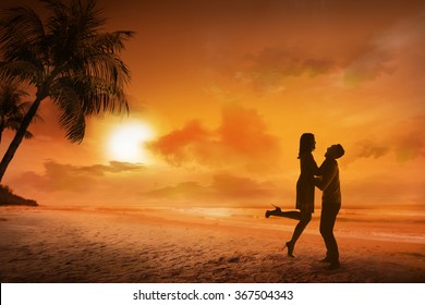 Young Couple Silhouette On A Beach On Sunset Background