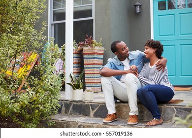 Young couple sit looking at each other outside their house - Powered by Shutterstock