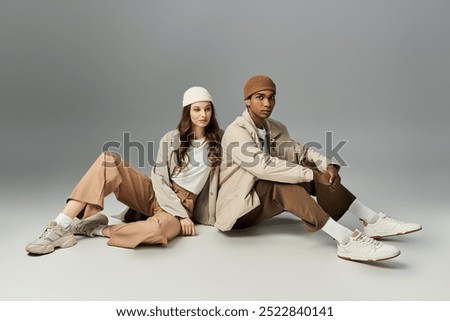A young couple sits in trendy autumn outfits, radiating style and warmth in vibrant hues.
