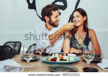 young couple sitting in a cafe and feed each other the juicy cakes